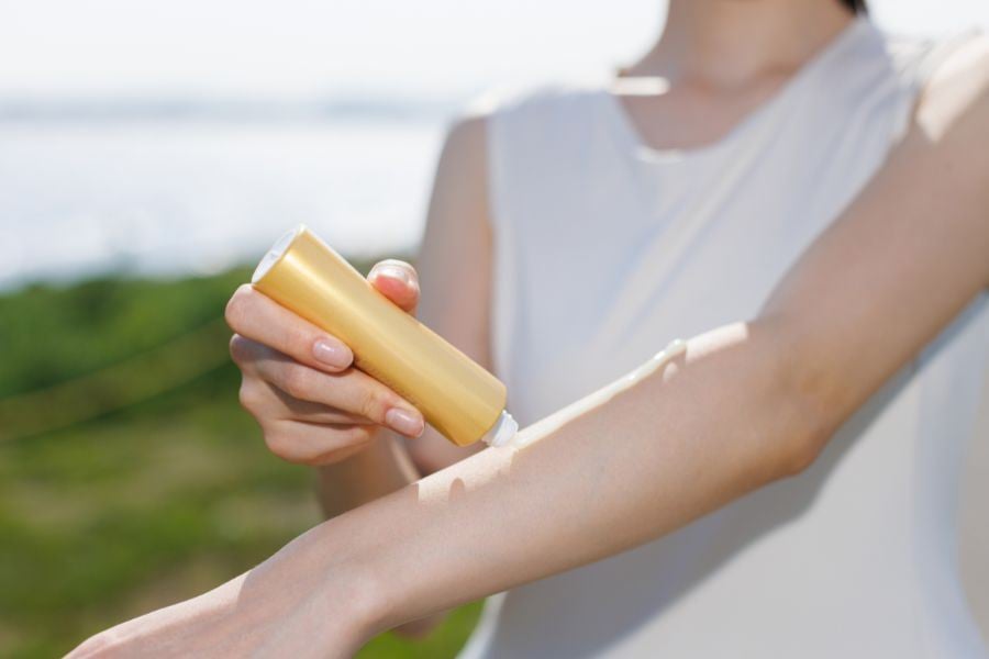Närbild på en person som stryker solkräm på sin arm