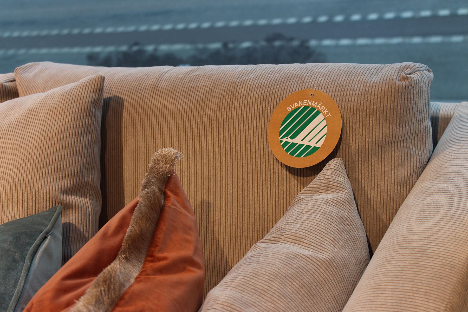 Närbild  på orange soffa med svanenmärkt tecken på